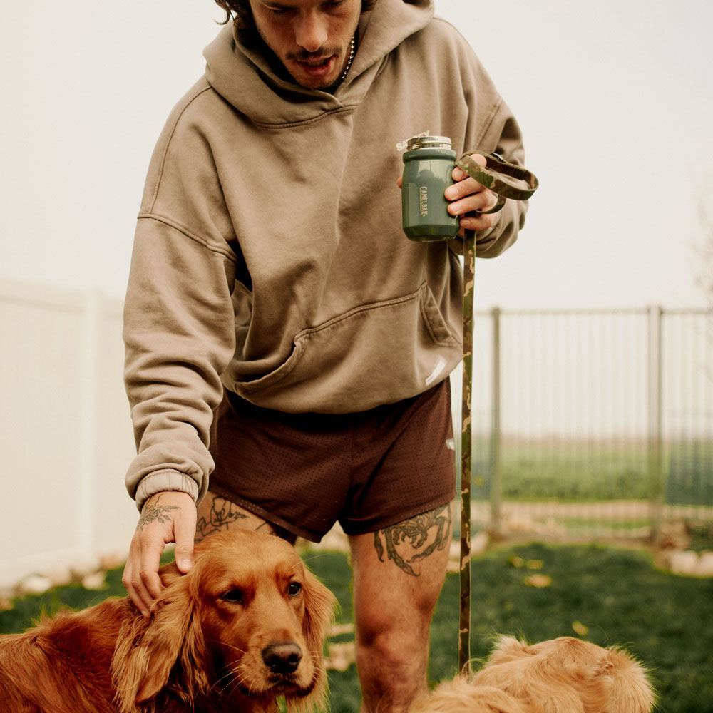 Model holding Camelbak bottle petting dog